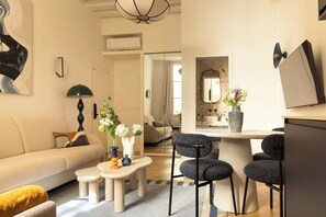 Ein modernes Wohnzimmer mit einer Couch, einem Couchtisch und einem Essbereich mit Stühlen und einem kleinen Tisch.