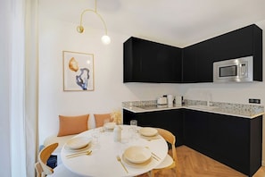 A modern kitchen with black cabinets, a white countertop, and a built-in microwave. - Chic Hideaway in Heart of Paris (Paris)