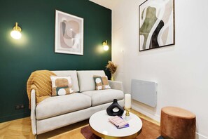 A living room with a sofa, a round coffee table, and two wall-mounted light fixtures. - Typical Parisian Flat next to the Louvre (Paris)