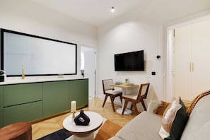 A compact living space with a kitchenette, a dining area, and a seating area with a sofa and chairs. - Typical Parisian Flat next to the Louvre (Paris)