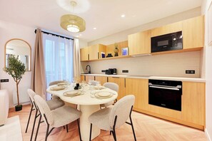 A modern kitchen with wooden cabinets, a microwave, a coffee maker, and a built-in oven. - Elegant & Calm Flat close to Eiffel Tower (Paris)