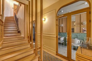 Eine Treppe führt zu einem Raum mit einer Holztür, einem Fliesenboden und einem Essbereich mit Stühlen und einem Tisch.