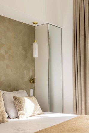 Quarto moderno com cama, almofadas, guarda-roupa e luminária suspensa.