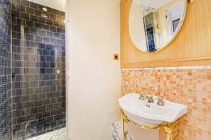 A bathroom with a white sink, gold fixtures, and a mirror above it. - Sweet Escape in Central Le Marais (Paris)