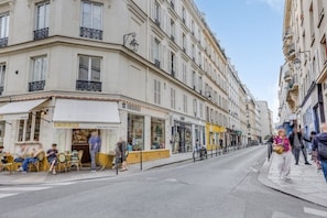 A street view with buildings, a restaurant named 'GINSBURGER,' and people sitting outside. - Sweet Escape in Central Le Marais (Paris)