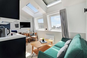 A modern apartment with a dining area, a sofa, and a kitchen area with a kettle. - Fabulous Getaway over the Parisian Clouds - 1BR (Paris)