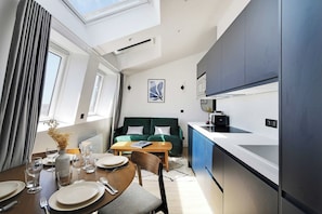 A modern kitchen with a dining area, a sofa, and a window with curtains. - Fabulous Getaway over the Parisian Clouds - 1BR (Paris)