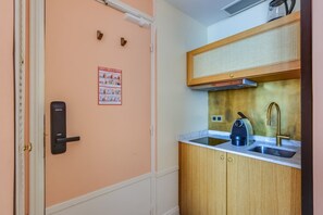 A compact kitchenette with a built-in stove, a coffee maker, and a sink. - Ideal Location in the Heart of Vibrant Le Marais (Paris)