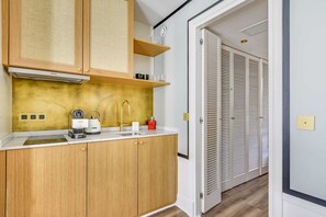A modern kitchen with wooden cabinets, a built-in stove, and a sink. - Ideal Retreat in a Peaceful Marais Area (Paris)