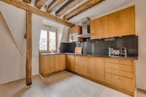Eine Küche mit Holzschränken, einer Edelstahl-Dunstabzugshaube und einem Fenster mit schmiedeeisernem Gitter.