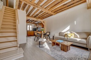 Un interior moderno con una escalera, un sofá, una zona de comedor y una cocina.