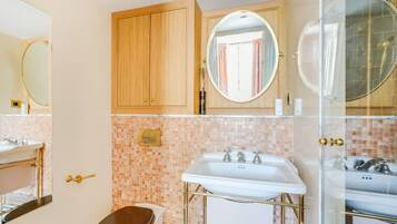 A bathroom with a toilet, a sink, a mirror, and a shower area.