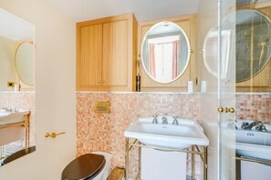 Un baño con inodoro, lavabo, espejo y zona de ducha.