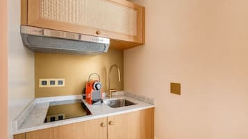 A compact kitchen with a built-in stove, a sink, and a wooden cabinet.