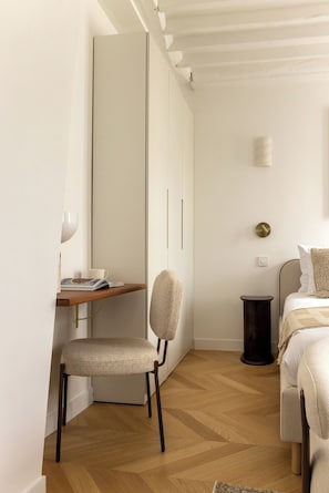 Ein Schlafzimmer mit Bett, Nachttisch, Lampe und einem Sessel.