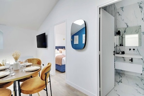 Ein modernes Hotelzimmer mit Essbereich, einem großen Spiegel und einem Badezimmer mit Marmorböden.