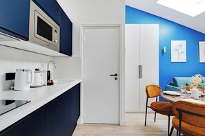 A modern kitchen with a microwave, coffee maker, and a dining area with a table set for two. - Dream Stay in the Parisian Sky - Voltaire/Nation (Paris)