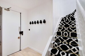 A staircase with a geometric black and white pattern, a white door with a black handle, and a wall-mounted light switch. - Dream Stay in the Parisian Sky - Voltaire/Nation (Paris)