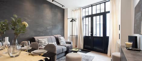 A modern living room with a sofa, dining table, and ottomans.