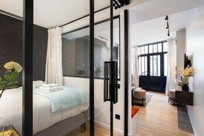 A modern bedroom with a large bed, a glass partition, and a view of the city. - Live Like Emily in Paris in Her Neighbourhood ! (Paris)