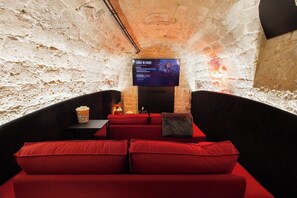 A cozy cinema room with red seating, a screen displaying 'EMILY IN PARIS', and a popcorn bucket on a table. - Live Like Emily in Paris in Her Neighbourhood ! (Paris)