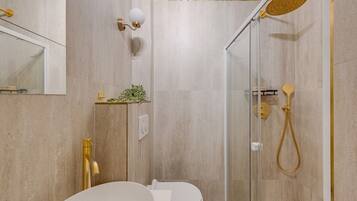 Une salle de bain moderne avec une douche à parois de verre, des toilettes blanches et un robinet doré.
