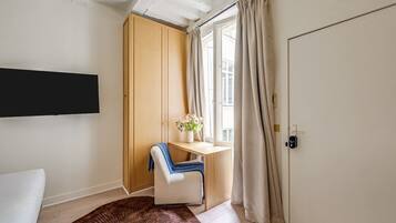 Une pièce comprenant un lit, un bureau, une chaise, une fenêtre avec des rideaux et une porte.