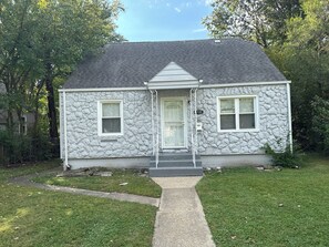 A two-story house with a stone facade, a front porch, and a mailbox. - Cozy 2-bedroom house in peaceful Harvey with AC (Harvey)