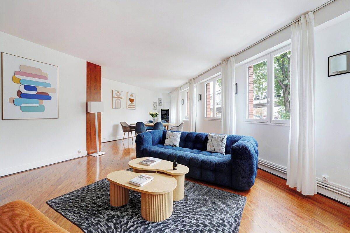 A modern living room with a blue sofa, two round coffee tables, and a patterned rug.
