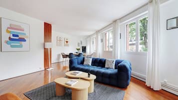 A modern living room with a blue sofa, two round coffee tables, and a patterned rug.