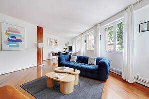 A modern living room with a blue sofa, two round coffee tables, and a patterned rug. - Contemporary Gem – Eiffel Tower & Metro Nearby (Paris)