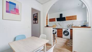 A compact kitchen with a washing machine, wooden cabinets, and a tiled backsplash.
