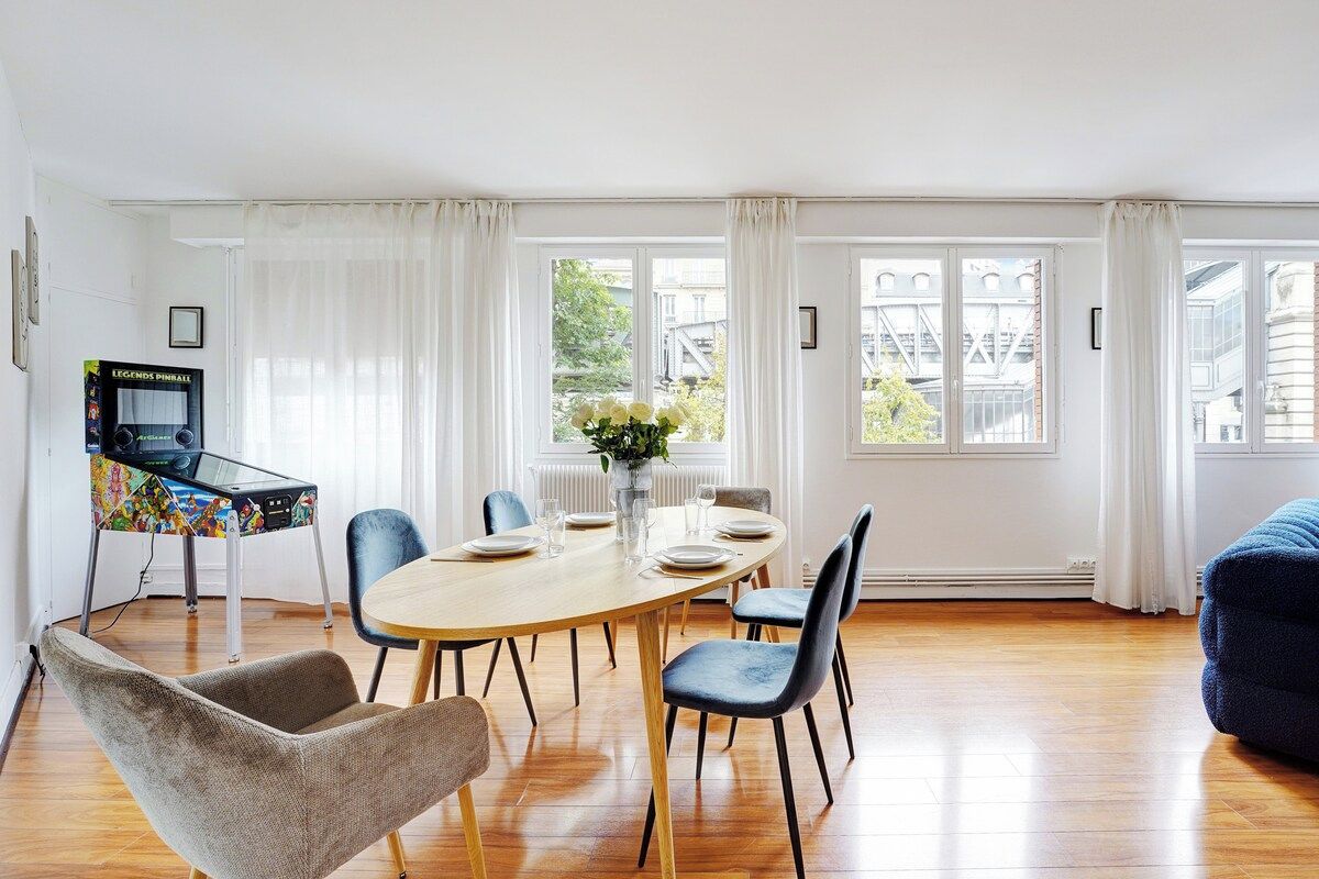 A dining area with a round table, chairs, and a television on a stand.