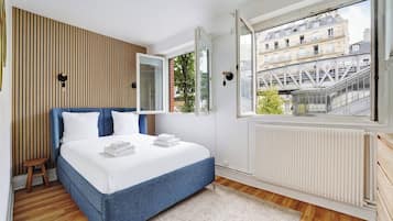 A bedroom with a bed, a window, and a view of buildings.
