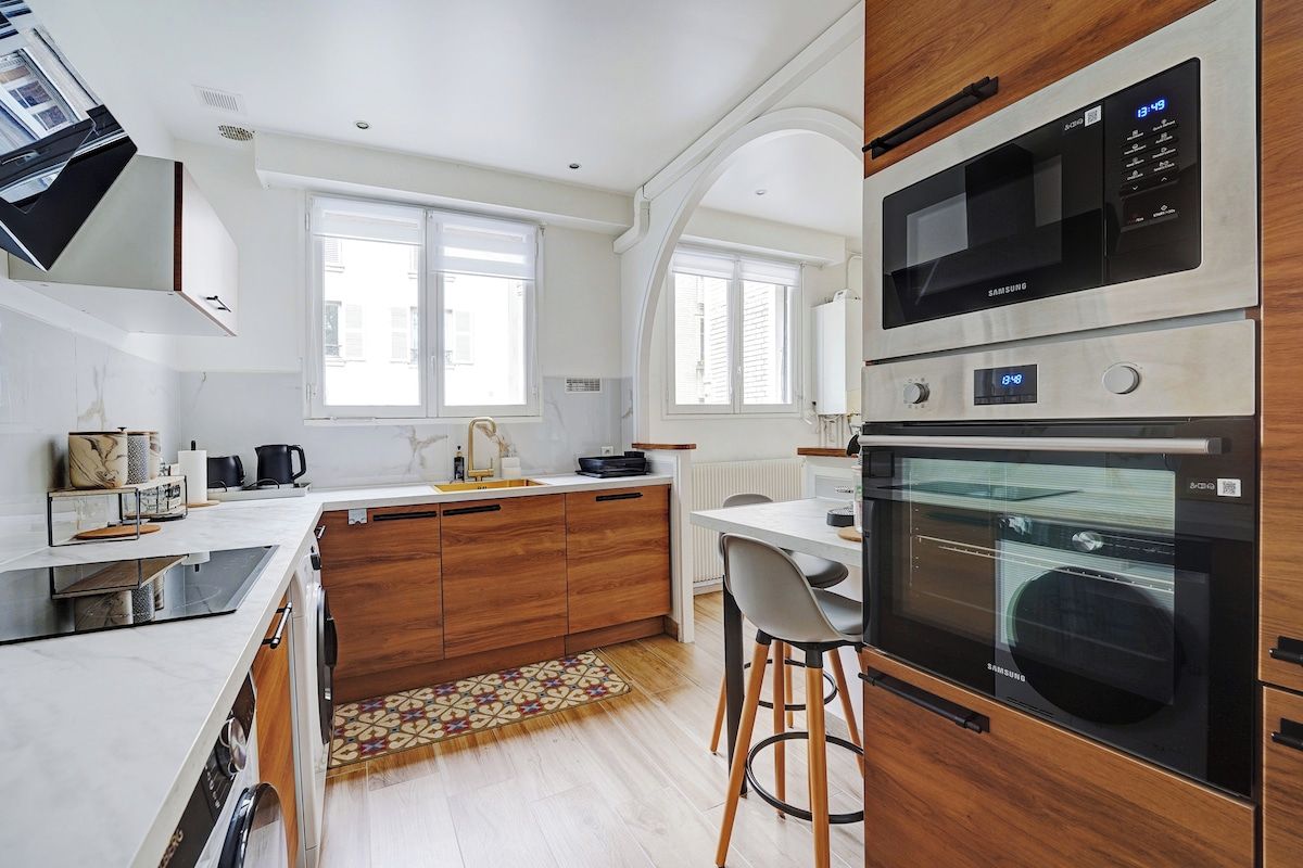 A modern kitchen with a microwave, oven, and a dining area with bar stools.