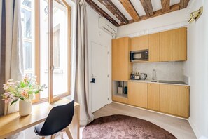 A compact kitchen with wooden cabinets, a microwave, and a sink. - Incredible Location - Central Studio near Louvre (Paris)