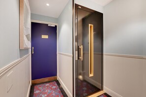 A hallway with a blue door, a glass door, and a patterned carpet. - Parisian Escape in Central Le Marais (Paris)