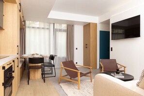 A modern living space with a dining area, a sofa, and a TV mounted on the wall. - Design Flat in Trendy Oberkampf Area (Paris)