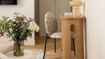 Een moderne woonkamer met een flatscreen televisie, een gestreept fauteuil, een houten bijzettafeltje met een lamp en een bloevas.