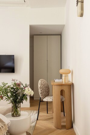 Een moderne woonkamer met een flatscreen televisie, een gestreept fauteuil, een houten bijzettafeltje met een lamp en een bloevas.