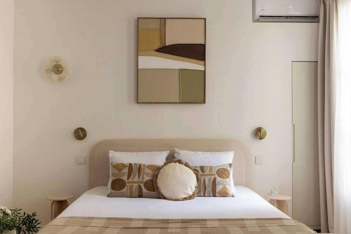 Een hotelkamer met een bed, een wandeling abstract schilderij, een ronde wandklok en een airconditioning.