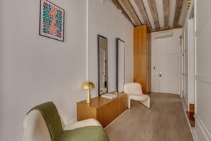 Una habitación con una cama, una mesita de noche con lámpara, un espejo y una puerta que da a otra habitación.