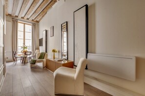 A modern living room with a sofa, a dining table with chairs, and a radiator. - Chic 1BR only Steps away from the Louvre (Paris)