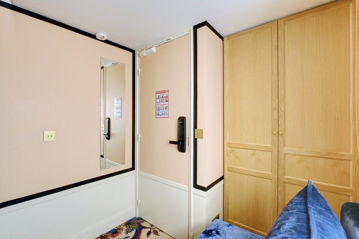 Une pièce comprenant un lit, une armoire, un miroir et une affiche accrochée au mur.