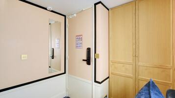 Une pièce comprenant un lit, une armoire, un miroir et une affiche accrochée au mur.