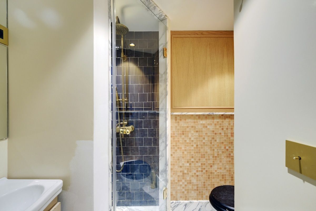 Une salle de bain avec une douche à parois de verre, un lavabo blanc et un meuble en bois.