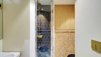 Une salle de bain avec une douche à parois de verre, un lavabo blanc et un meuble en bois.