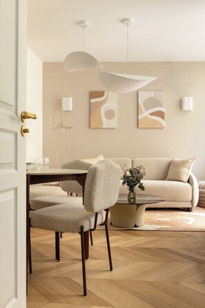 A modern living room with a dining area, featuring a sofa, chairs, a coffee table, and abstract wall art. - Redesigned Calm Retreat in the Heart of Le Marais (Paris)
