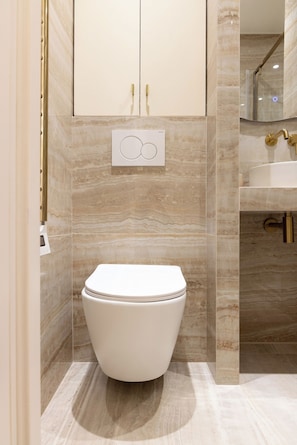 A modern bathroom with a toilet, a vanity with a sink, and a shower area. - Redesigned Calm Retreat in the Heart of Le Marais (Paris)