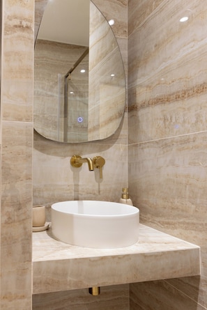 A modern bathroom with a marble vanity, a round mirror, and a gold faucet. - Redesigned Calm Retreat in the Heart of Le Marais (Paris)